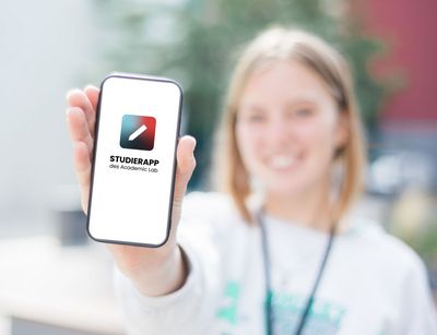 Eine Studentin hält ein Smartphone mit geöffneter Studierapp. Foto: Academic Lab
