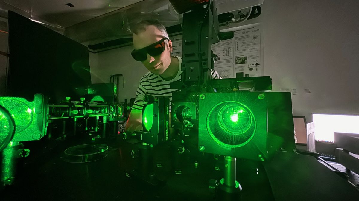 zur Vergrößerungsansicht des Bildes: Forscher, der an einem optischen Aufbau mit grünem Laserlicht arbeitet